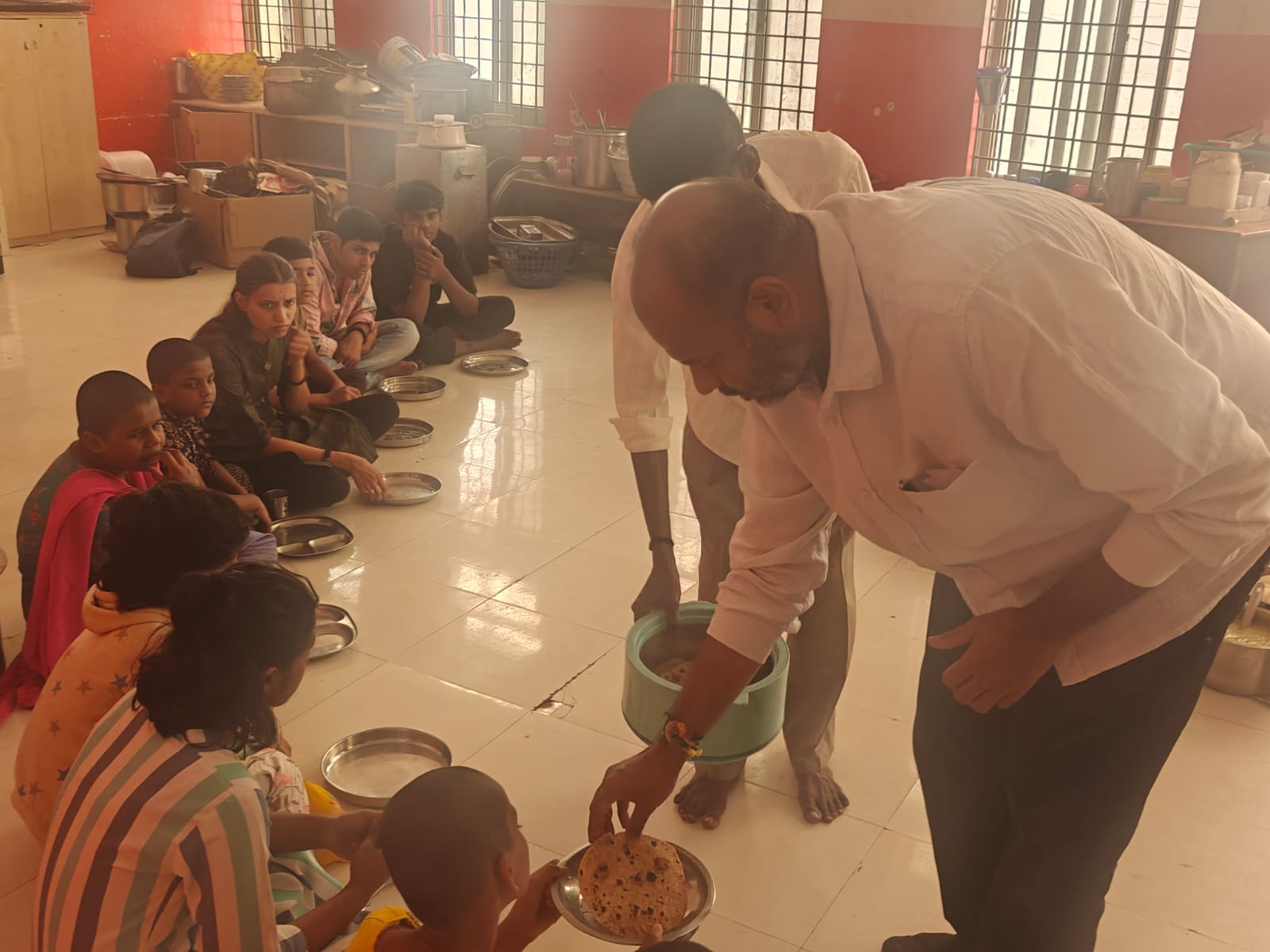 Mr. K.H. Radharaman of Angadi Foundation Bengaluru serving food to children during a humanity welfare meal service.